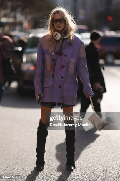 Lindsay Vrckovnik seen wearing a purple oversized jacket, shorts, Apple earpods max, a beige bag and black boots before the Coach show on February...