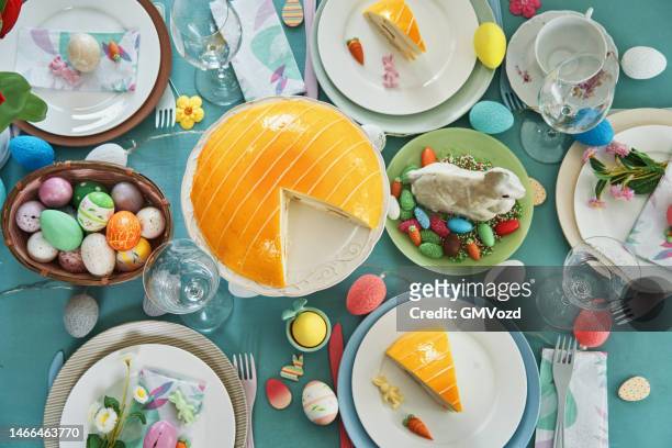 colorful decorated easter table with easter eggs, flowers and carrot easter cake - paastaart stockfoto's en -beelden