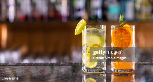 gin tonic cocktails with lime, lemon and red oranges on bar counter in pup or restaurant. - cocktail counter stock-fotos und bilder