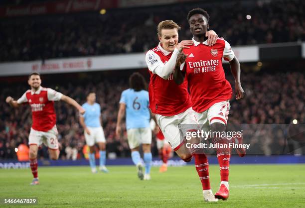 Bukayo Saka of Arsenal celebrates with teammate Martin Odegaard after scoring the team's first goal from a penalty kick during the Premier League...