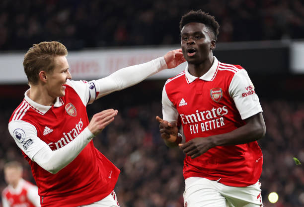 Bukayo Saka of Arsenal celebrates with teammate Martin Odegaard after scoring the team's first goal from a penalty kick during the Premier League...
