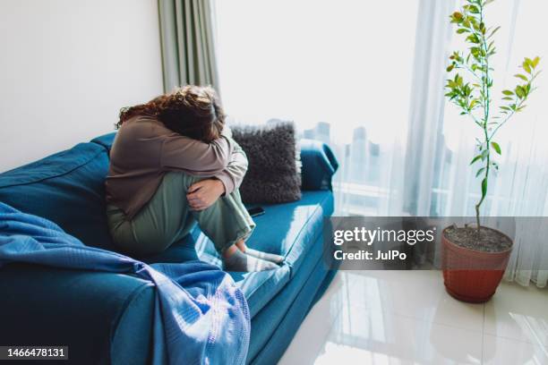 depressive erwachsene frau auf dem sofa zu hause - mental illness stock-fotos und bilder