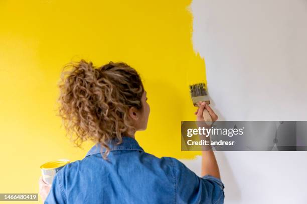 woman at home painting a wall yellow - painting on wall stock pictures, royalty-free photos & images