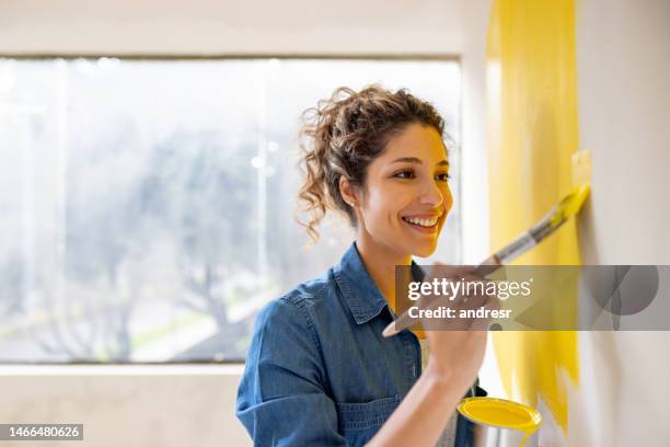 woman remodeling her house and painting a wall yellow - yellow wall stock pictures, royalty-free photos & images