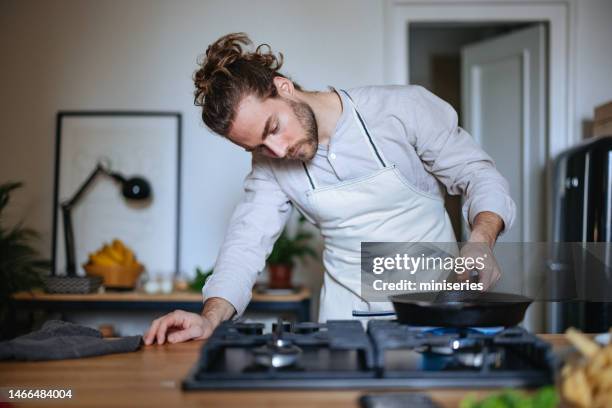 serious man making a healthy meal in the kitchen - gas appliances stock pictures, royalty-free photos & images