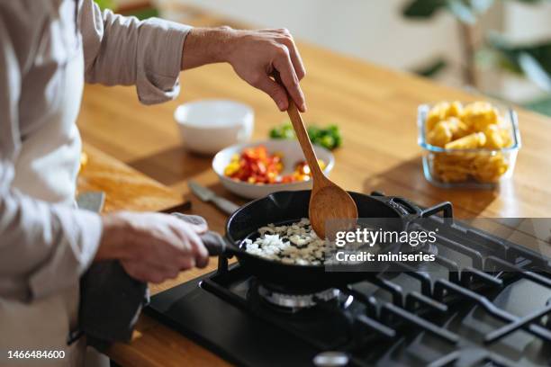 foto de cerca de las manos de manâs preparando el almuerzo en la sartén en casa - sartenes fotografías e imágenes de stock