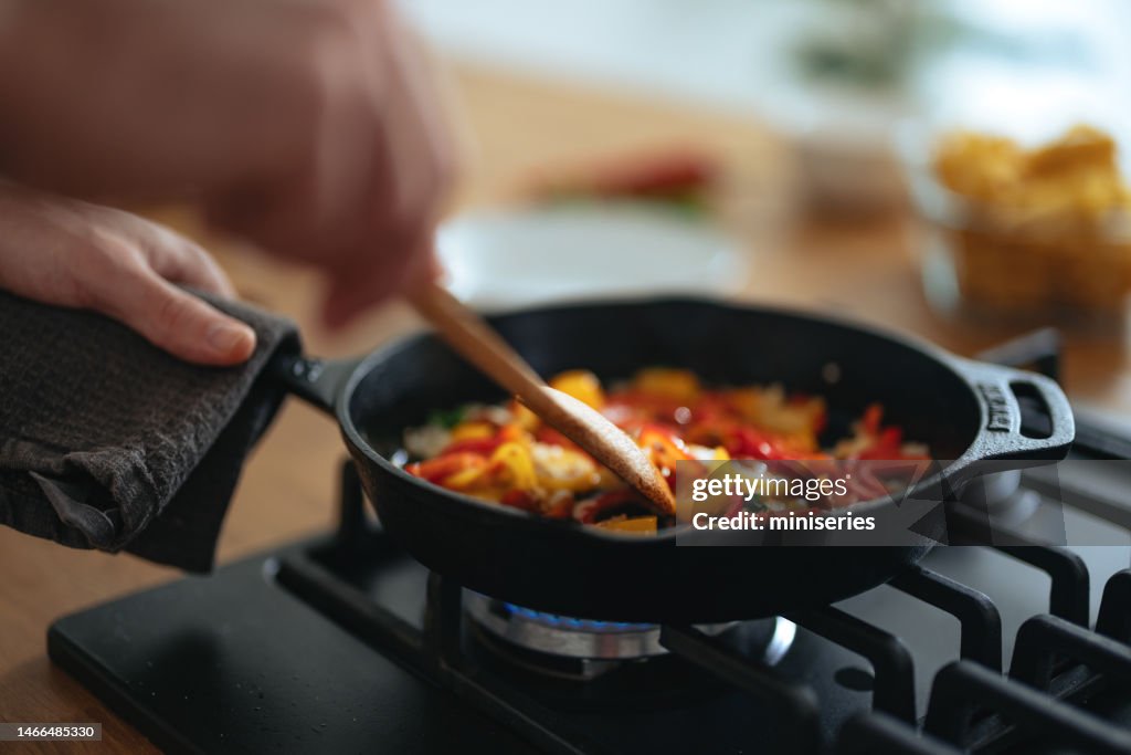 Foto de perto das mãos do homem preparando um almoço saudável na panela em casa