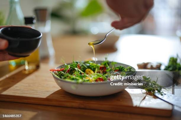 photo en gros plan des mains de l’homme ajoutant de la vinaigrette à une salade à la maison - vinaigrette dressing photos et images de collection