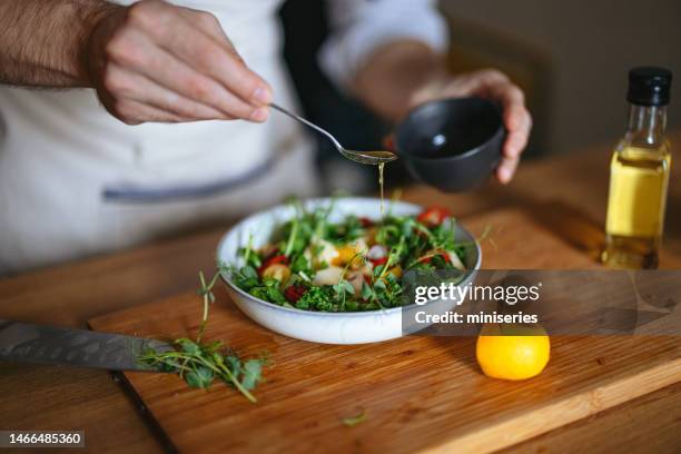 close up photo of manâs hands adding dressing to a salad at home - food dressing 個照片及圖片檔