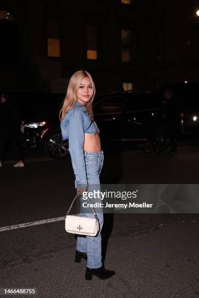 Fashion Week Guest seen wearing a full Tory Burch look, a denim jeans jacket, denim jeans pants and bralette and black heels and a white Tory Burch...