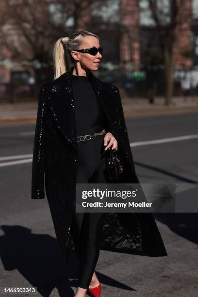 Denisa Palsha wearing Michael Kors Collection shiny sparkling black long coat, gold logo Michael Kors belt and Michael Kors black and gold shades,...