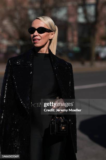 Denisa Palsha wearing Michael Kors Collection shiny sparkling black long coat, gold logo Michael Kors belt and Michael Kors black and gold shades,...