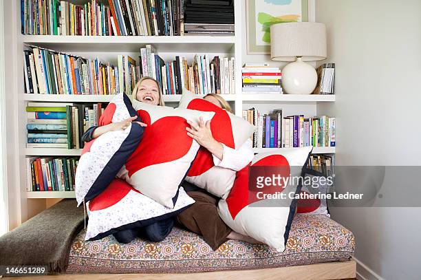 two women hugging heat shaped pillows - cushion stock-fotos und bilder