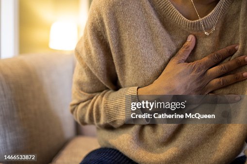 Black woman experiences chest pain sitting on sofa Black woman experiences chest pain sitting on sofa