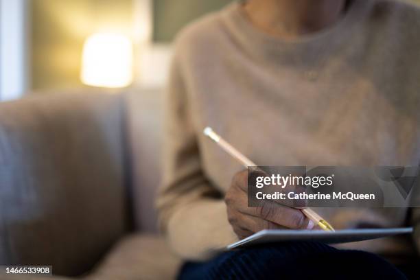 black woman holding note pad & pencil sitting on sofa - note pad 個照片及圖片檔