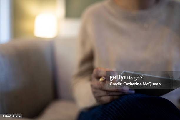 black woman holding note pad & pencil sitting on sofa - dear diary stock pictures, royalty-free photos & images