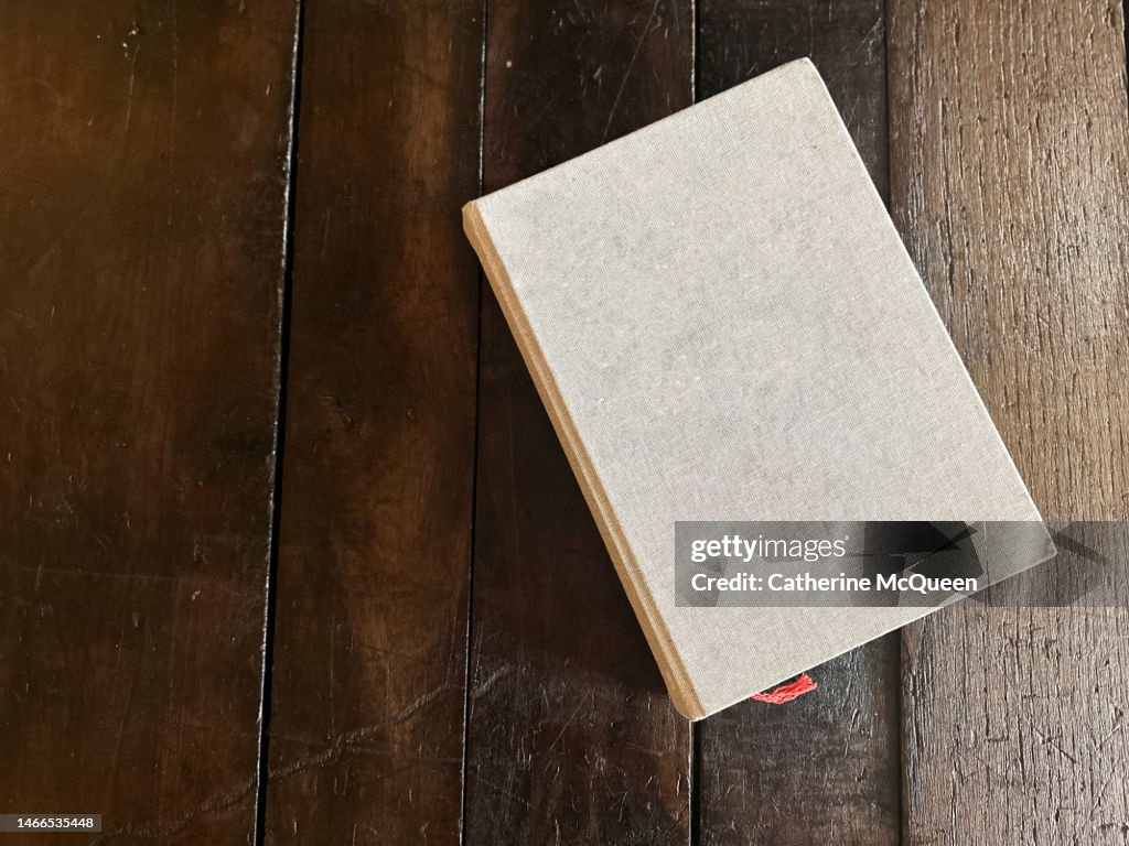 Blank linen covered coffee table book on wooden table (copy space)