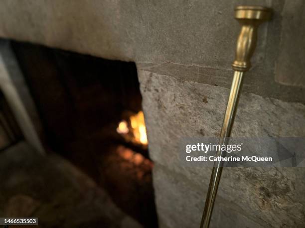 cozy fire roaring in stone fireplace - utensilios para chimenea fotografías e imágenes de stock