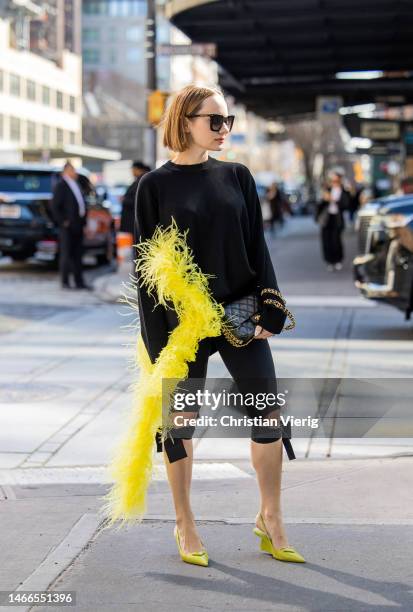 Katya Bychkova wears black jumper with appliquéd feathers in yellow, black tight shorts, pointed Prada heels, Chanel bag, sunglasses outside Michael...