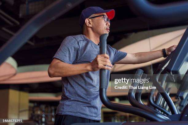 asiatischer mann für mittlere erwachsene beim sport im fitnesscenter - cross trainer stock-fotos und bilder