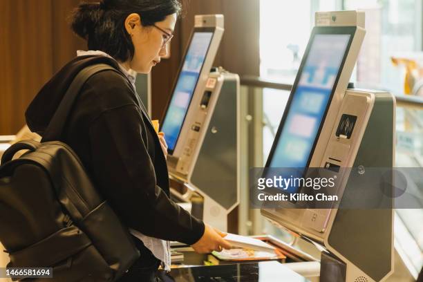 asian female adult student using self check out in public library - counter stand stock-fotos und bilder