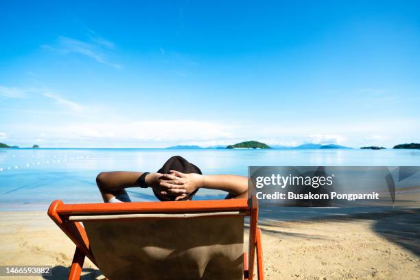 man sitting on deck chair on sandy beach - man on the beach relaxing in deckchair fotografías e imágenes de stock