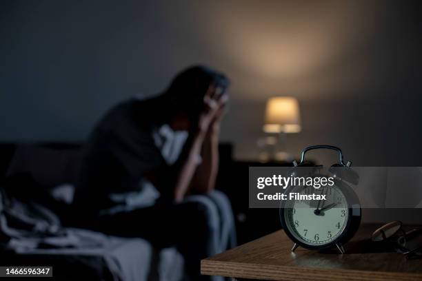 un hombre asiático deprimido sentado en la cama no puede dormir de insomnio - insomnio fotografías e imágenes de stock