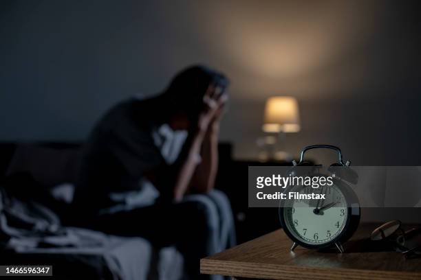 depressed senior asian man sitting in bed cannot sleep from insomnia - slaappil stockfoto's en -beelden