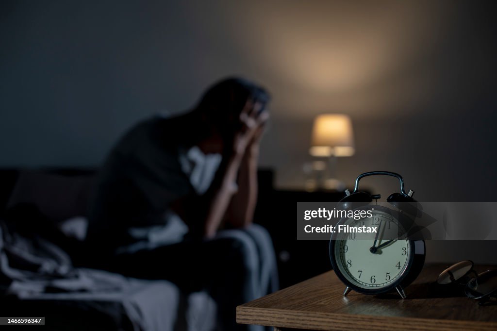 Depressed senior Asian man sitting in bed cannot sleep from insomnia