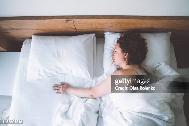 top view unhappy mature woman lying alone in bed and touching empty space next to her with hand - 寡婦 ストックフォトと画像