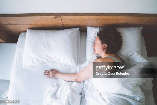 top view unhappy mature woman lying alone in bed and touching empty space next to her with hand - widow stock pictures, royalty-free photos & images