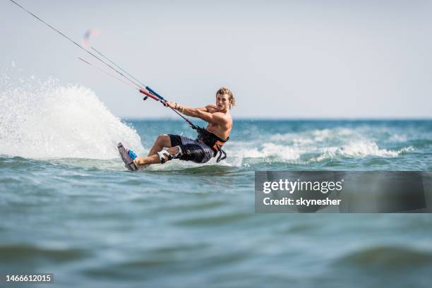 young man enjoying in kiteboarding during summer day at sea. - kiteboard stockfoto's en -beelden