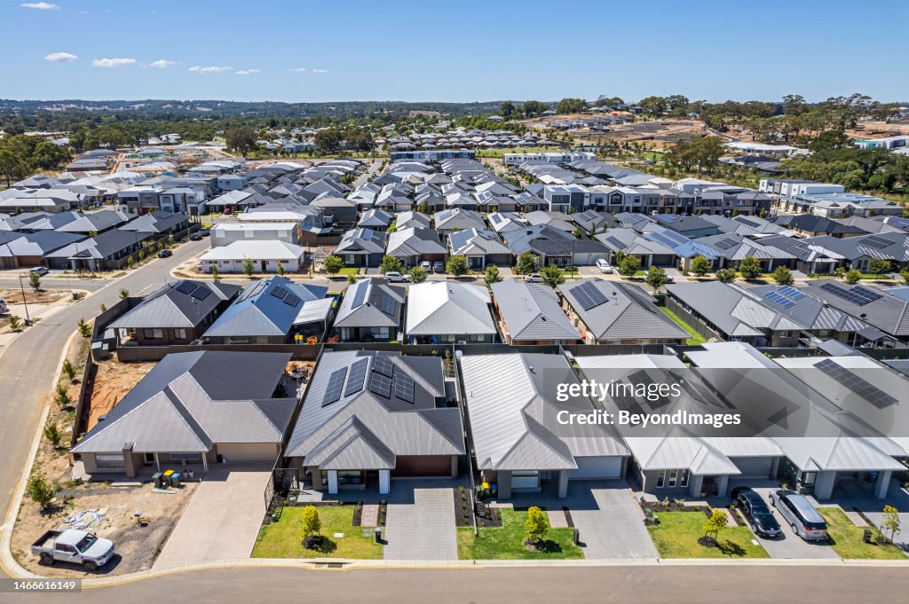 Niedrige Luftaufnahme aus nächster Nähe neue dichte ländliche Wohnsiedlung, meist graue Dächer, einige grüne Landschaftsgestaltung, junge Bäume