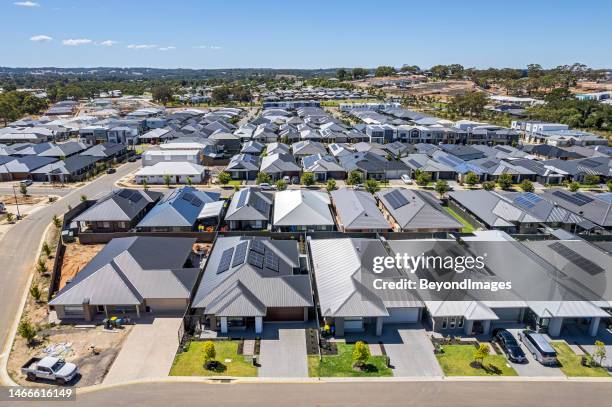 low aerial close view new dense rural housing development, mostly grey roofing, some green landscaping, young trees - digital devices beside each other stockfoto's en -beelden