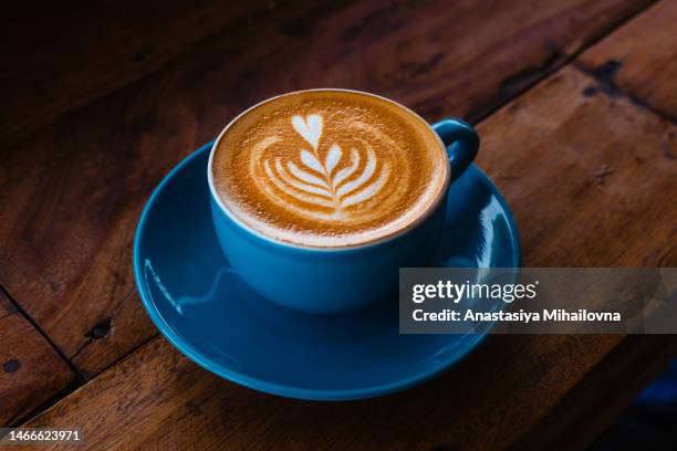 cappuccino in a blue ceramic mug on a wooden table side view - milchkaffee stock-fotos und bilder