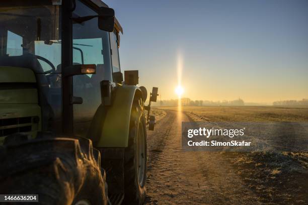tractor parked on an agricultural path in the evening during sunset with back lit and sun at the horizon - agriculture supply chain technology stock pictures, royalty-free photos & images
