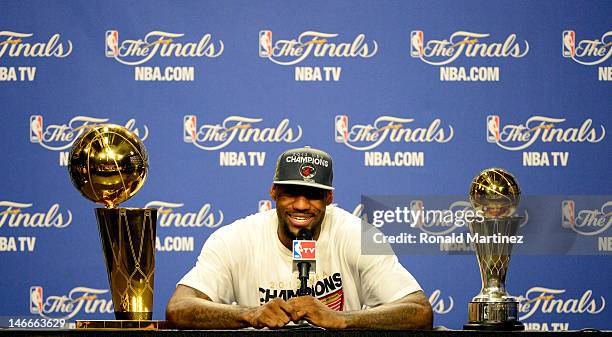 LeBron James of the Miami Heat answers questions from the media next to the Larry O'Brien Finals Championship trophy and James' Bill Russell Finals...