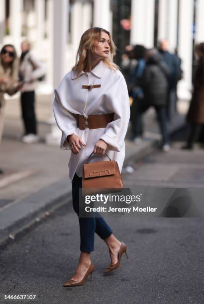 Chloe Lecareux seen wearing a brown bag by Carolina Herrera, a white oversized jacket with a brown belt, tight dark blue jeans and brown high heels...