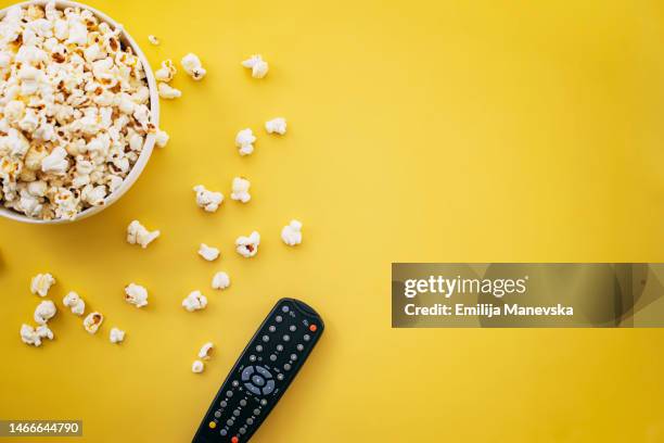 popcorn and tv remote controller on yellow background - remote stock pictures, royalty-free photos & images