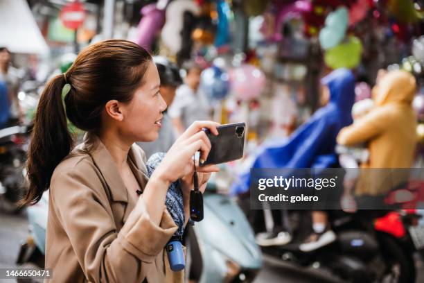 woman taking mobile video in streets of hanoi - modern vietnam imagens e fotografias de stock