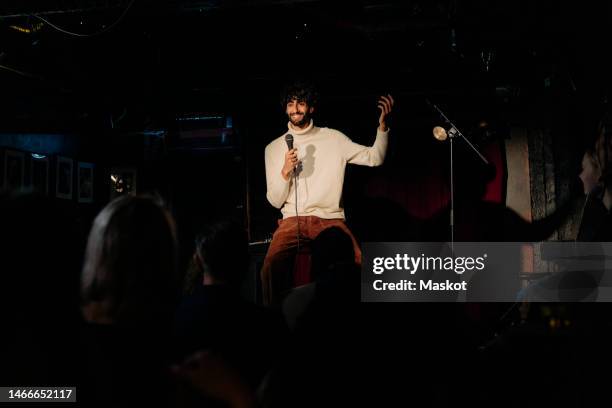 smiling young male comedian performing stand-up on stage in theater - un solo hombre fotografías e imágenes de stock