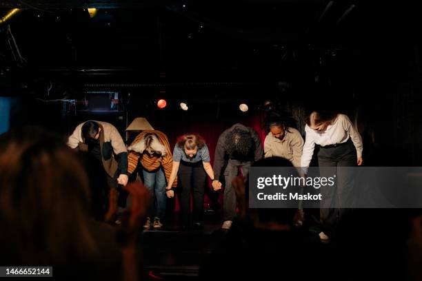 multiracial male and female actors holding hands and bowing together on stage at theater - amateur theater stockfoto's en -beelden