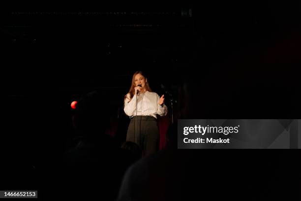 young female comedian performing stand-up on stage in amateur theater - comedian mic stock pictures, royalty-free photos & images