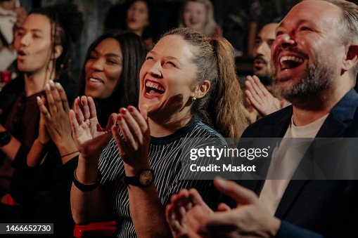 Multiracial audience laughing and applauding while watching comedy stage show in theater Multiracial audience laughing and applauding while watching comedy stage show in theater
