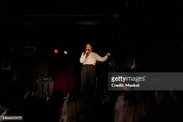 young female comedian performing stand-up for audience at amateur theater - stand up comedian - fotografias e filmes do acervo