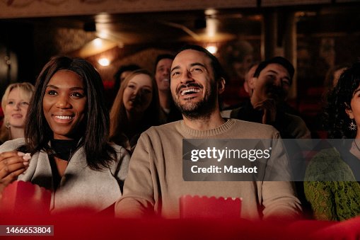 Cheerful multiracial friends laughing while enjoying comedy movie in cinema theater Cheerful multiracial friends laughing while enjoying comedy movie in cinema theater