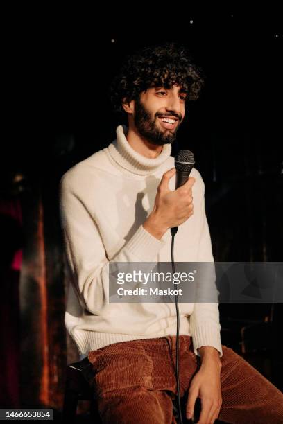 smiling young man performing stand-up comedy on stage in theater - stand up comedy ストックフォトと画像