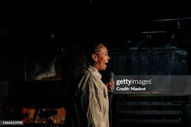 young woman laughing while performing stand-up comedy at amateur theater - stand up comedy stockfoto's en -beelden