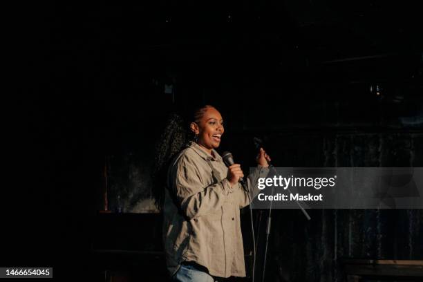 cheerful young woman performing stand-up comedy at stage theater - comedian foto e immagini stock