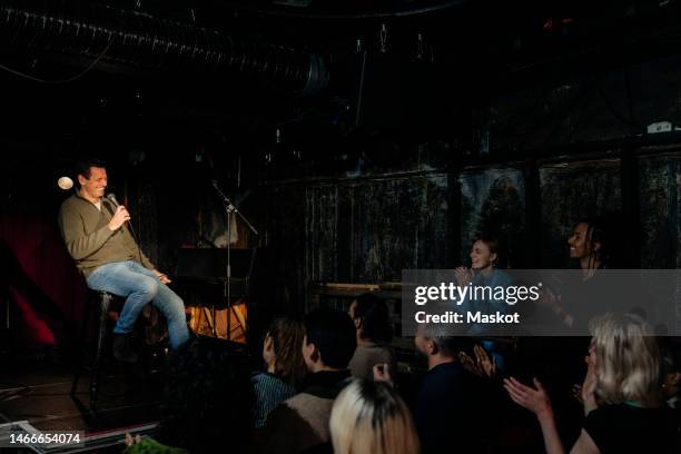 smiling senior male comedian performing in front of audience on stage at amateur theater - comedian fotografías e imágenes de stock